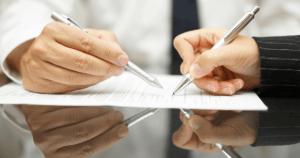 Man Hand Pointing Out Where to Sign as Woman Hand Signs Document