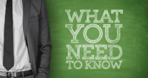 What You Need to Know Written on Green Chalkboard with Businessman Standing to the Left