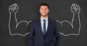 Businessman Standing in Front of Chalkboard with Muscular Chalk Arms Drawn Behind Him