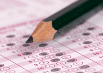 Pink Scantron in Deep Focus with Answers Filled in and Black Pencil in Foreground