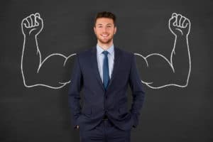Businessman in Front of Chalkboard with Muscular Arms Drawn Behind