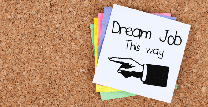Dream Job This Way Written with Drawn Hand Pointing Left on Top Sticky Note in Pile on Cork Background